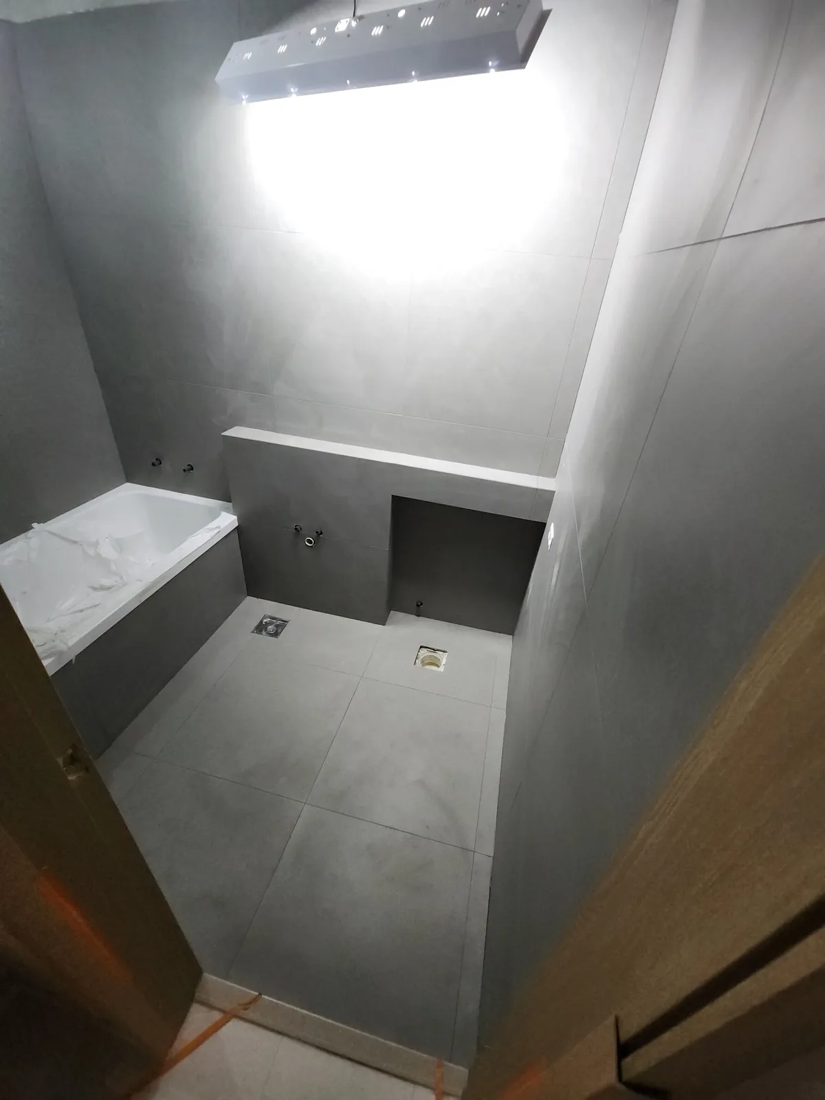 철거를 마친 욕실 내부가 회색 대형 타일로 벽과 바닥까지 통일감 있게 마감된 상태로 보인다.